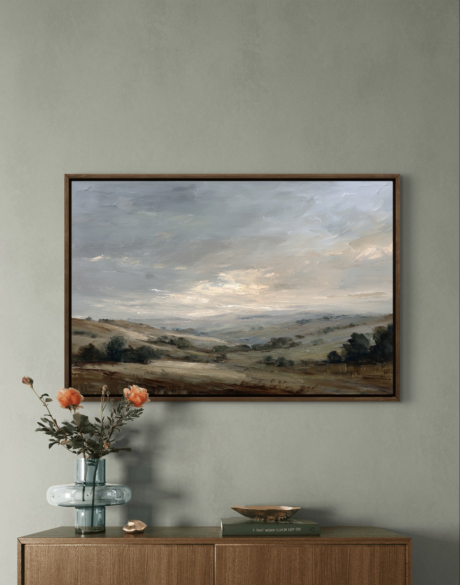 Framed landscape painting on a wall above a wooden console table with decorative items.